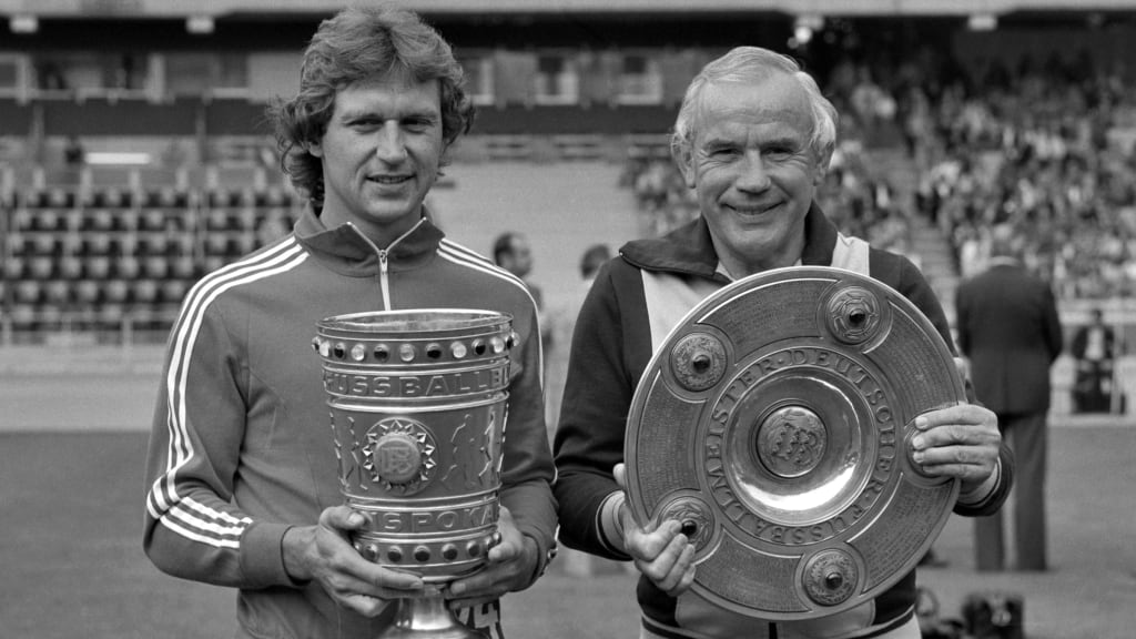 Heinz Flohe (links) und Trainer Hennes Weisweiler präsentieren stolz ihre Trophäen nach dem Double-Gewinn des 1. FC Köln.