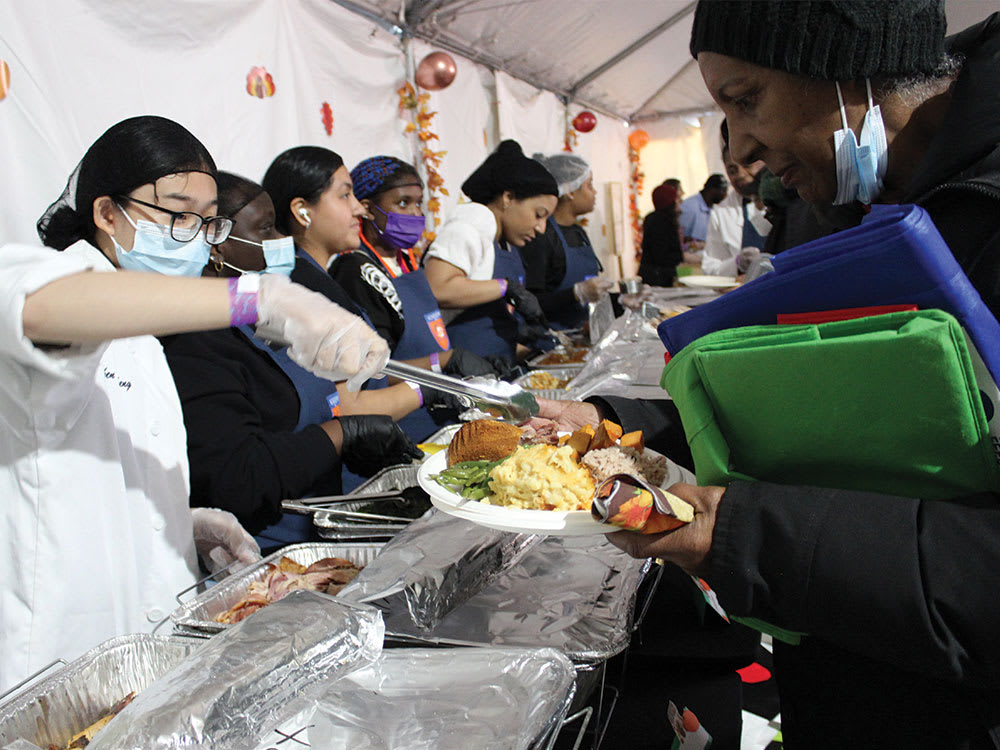 A shot of volunteers providing lunches to community members during the KingsCares annual Thanksgiving luncheon.